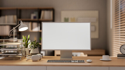 A computer mockup and office supplies on a wooden desk in a contemporary minimalist office.