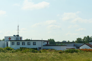 Fototapeta premium A serene view of a medical building surrounded by greenery on a sunny day with clear skies and distant trees
