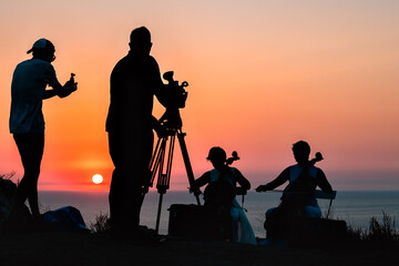 Obraz premium Hymn to the setting sun. Concert of a cello duet against the backdrop of sunset