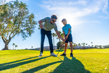 Coach teaching a young boy to play golf in a course