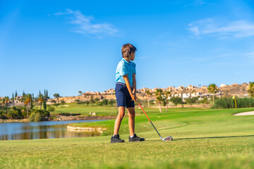 Young golfer learning to play golf in a course