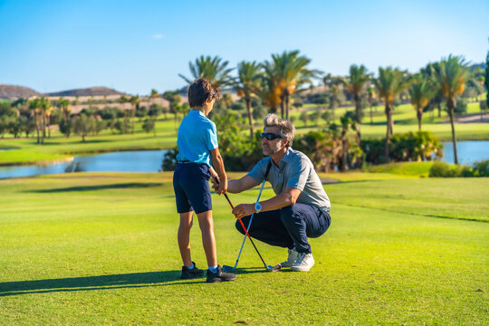 Instructor correcting and guiding a boy during golf lesson