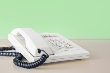 Desk phone 80s 90s on table against green wall copy space