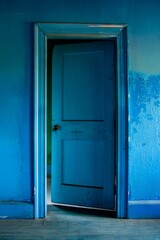 A blue door in an abandoned building with peeling paint on the walls