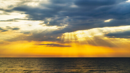 Orange sunrise sunrise over sea horizon. Sun rays light drop on colorful clouds on sky.