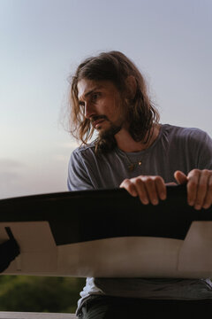 A man surfer is looking at a new surfboard.
