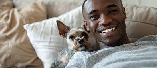 African American man smiles with small dog on couch camera flash illuminates the portrait s simplicity with space for additional text or image