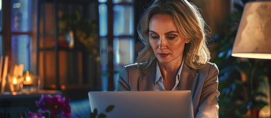 Middle aged businesswoman aged 45 working on a computer in an office setting She is an executive and an HR manager using a laptop at her work desk with available copy space image for ads