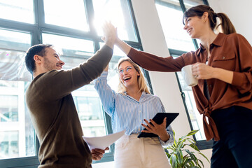 Happy business colleagues doing high-five standing in office