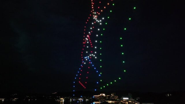 light show by drones over city at night