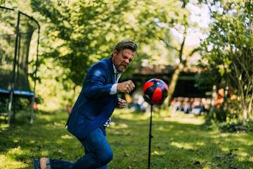 Angry businessman hitting punching bag at park