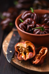 Ripened chocolate habanero peppers (capsicum chinense) on wooden cutting board. Very hot mexican peppers on rustic wooden table close up