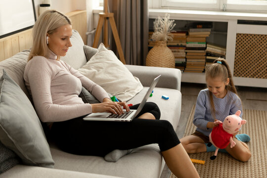 Mother using laptop near daughter at home