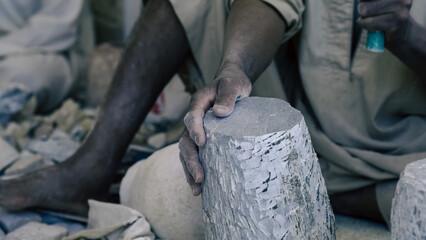 hands of a male Egyptian sculptor while working with a stone alabaster
