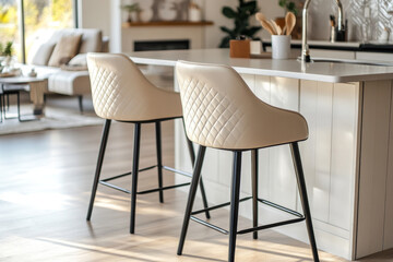 Fototapeta premium Beige leatherette barstools with quilted backrest and black metal base in boho-style kitchen island setting.