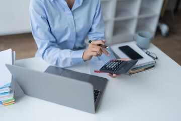 woman meticulously plans a finance audit, using a computer and calculator to review budget...