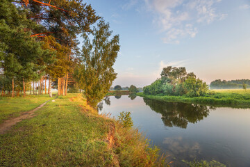 Obraz premium A peaceful scene of a river with trees and grass in the background