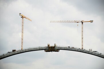 Cranes working on the construction of a large bridge over the river.