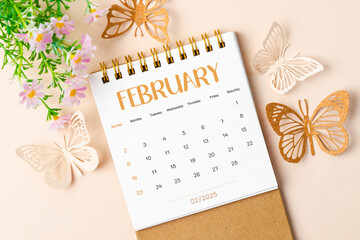 February 2025 desk calendar and paper butterfly with flower.