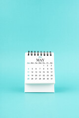 May 2025 white desk calendar on blue background.