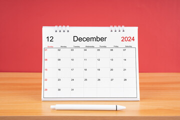 December monthly desk calendar for 2024 year and pen on the wooden table.