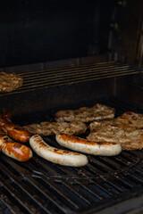 A close-up of a barbecue grill loaded with grilled sausages and seasoned steaks, showcasing the deliciously charred and juicy meat. Perfect for a summer cookout or a weekend barbecue feast