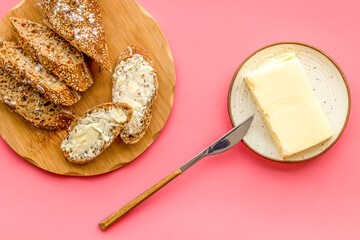 Slice of bread with butter on pink background top view