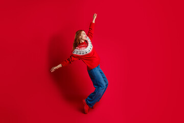 Photo of funky young energetic lady wearing ugly sweater standing tiptoes having fun christmas theme party isolated on red color background