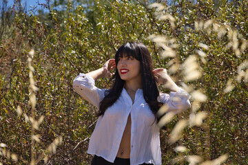 Woman, young, beautiful, Latina, brunette, with white shirt and black shorts, looking distracted and thoughtful, in the middle of nature. Concept beauty, looks, spring, nature.