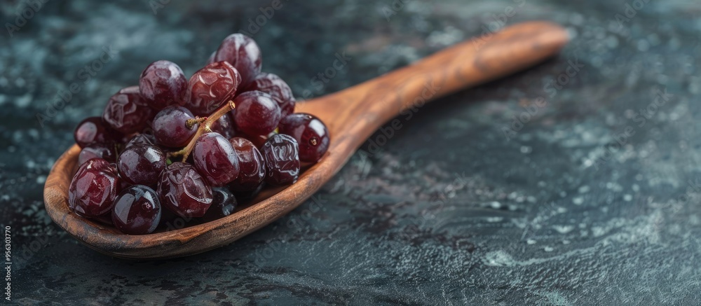 Poster dried grapes on a wooden spoon displayed against a dark backdrop with copy space image