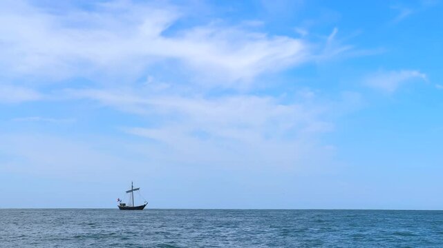traditional historic dutch sailboat kamper kogge at sea under blue sky with flag of the Netherlands holland at stern of boat at open sea or ocean