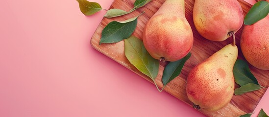 A wooden board featuring fresh pears and leaves set against a pink backdrop with copy space image