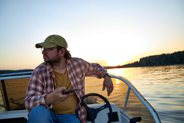 Obraz premium a man sits in a boat on a river and looks at his phone