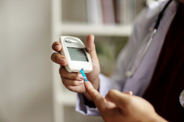 Doctor check diabetes from finger blood sugar level with finger lancet.