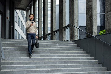 Businessman descends urban stairs while focused on smartphone, demonstrating modern professional...