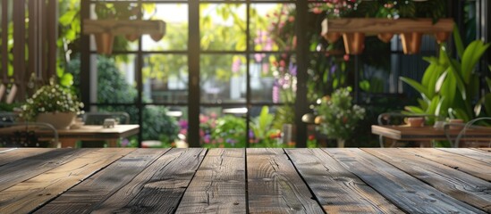 Fototapeta premium Wooden table in the foreground with cafe ambiance in the background and a large window overlooking a garden ideal for showcasing products with copy space image