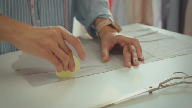 Craftsman. Trendy European woman working on costume details draws lines with special fabric chalk. Cinematic shot model woman uses industrial chalk to draw on fabric, fashion trends