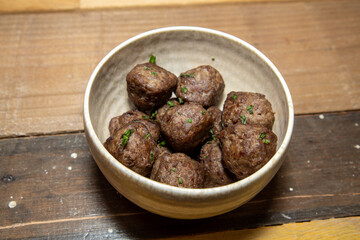 A bowl of delicious meatballs on a wooden kitchen work top