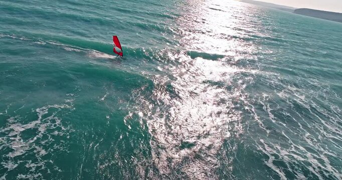 air view windsurfing in the sea. Active sea sports. A board with a sail floats on the waves of the ocean. High quality 4k footage
