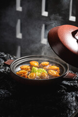 Abalone delicacy in a bowl with lid open, black background, indoor shot