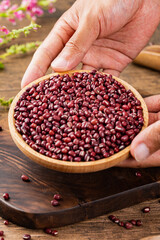 Red beans in a wooden bowl, on a wooden table indoors, close up