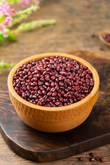 Red beans in a wooden bowl, on a wooden table indoors, close up