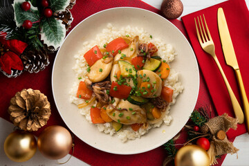 Wok-fried calmares with vegetables over white rice. Food on a table with Christmas decorations.