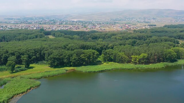 Aerial shot Lake near forest. Drone shot lake and forest on town background. Sevan lake in Armenia, Caucasus. Green lake.