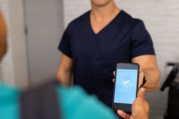 Handing smartphone with verification screen to medical professional in medical clinic