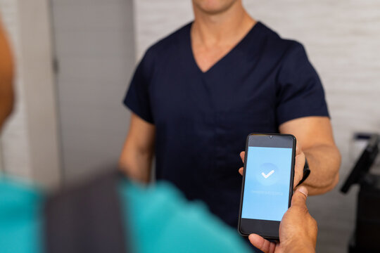 Handing smartphone with verification screen to medical professional in medical clinic