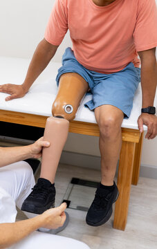 Fitting prosthetic leg, technician assisting patient in medical lab setting