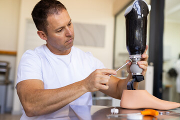 Technician adjusting prosthetic leg with tools in prosthetic lab, focusing intently