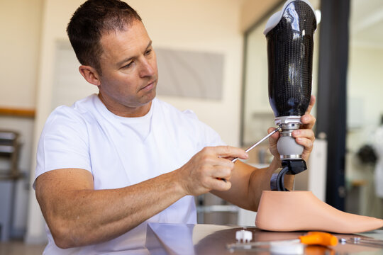 Technician adjusting prosthetic leg with tools in prosthetic lab, focusing intently