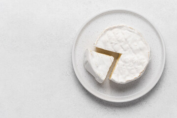 Soft camembert cheese on plate on white background top view with copy space